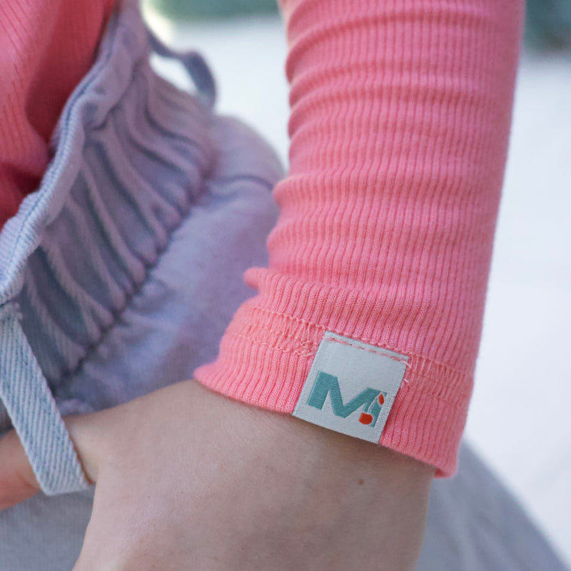 Close-up of a pink sleeve with a brand label on a blurred background