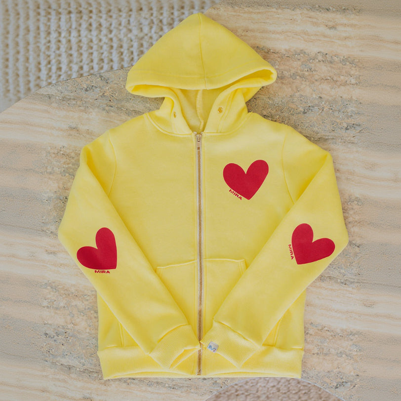 Yellow hoodie with red hearts on a textured surface