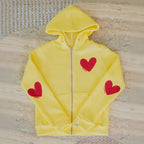 Yellow hoodie with red hearts on a textured surface