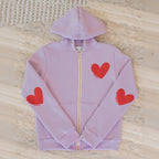 Purple hoodie with red heart designs on a textured surface