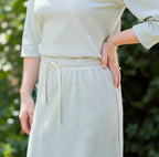 Person wearing a light-colored knit top and skirt with a blurred background