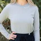 Person wearing a light gray long-sleeve shirt and black pants outdoors.