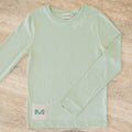Light green long-sleeve shirt with a brand label on a beige surface