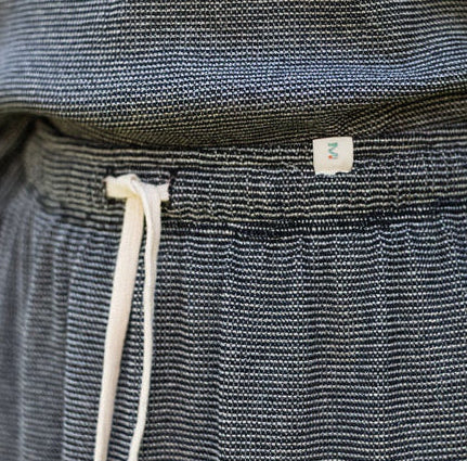 Dark woven garment with a drawstring and visible brand label.